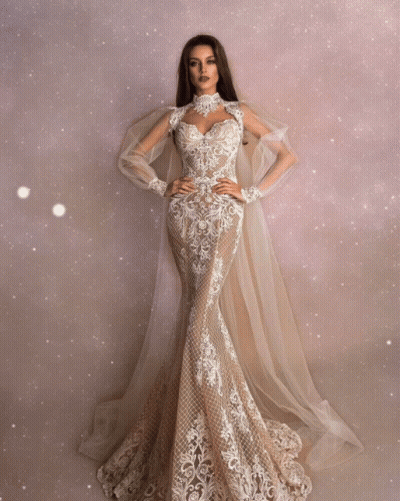 A Woman Is Wearing A Long White Dress With A Cape GIF