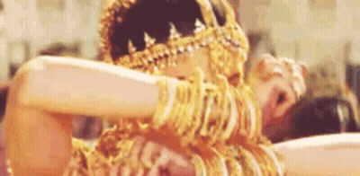 A Woman Is Wearing A Lot Of Gold Jewelry And Dancing . GIF