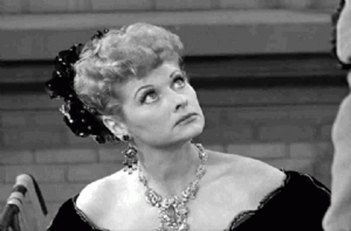 A Woman Is Wearing A Necklace And Earrings And Looking Up . GIF