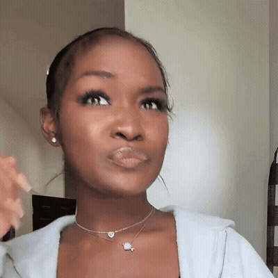 A Woman Is Wearing A Necklace And Earrings And Making A Face . GIF