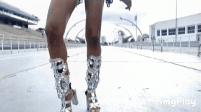 A Woman Is Wearing A Pair Of Silver High Heels . GIF