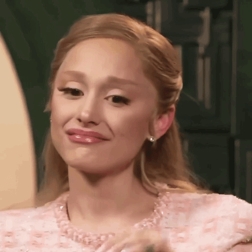 A Woman Is Wearing A Pink Dress And Earrings And Making A Funny Face . GIF