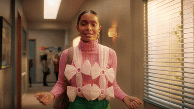 A Woman Is Wearing A Pink Sweater With Bows On It . GIF
