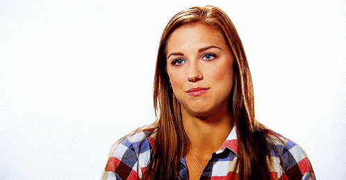 A Woman Is Wearing A Plaid Shirt And Making A Face . GIF