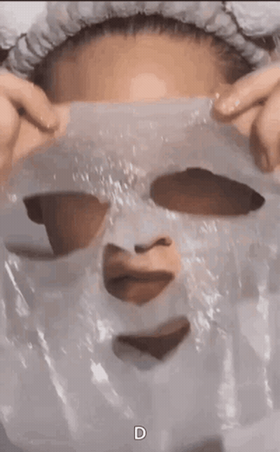 A Woman Is Wearing A Plastic Mask On Her Face With A Heart Cut Out Of It . GIF