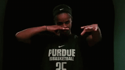 A Woman Is Wearing A Purdue Basketball Shirt And Covering Her Mouth With Her Hands . GIF