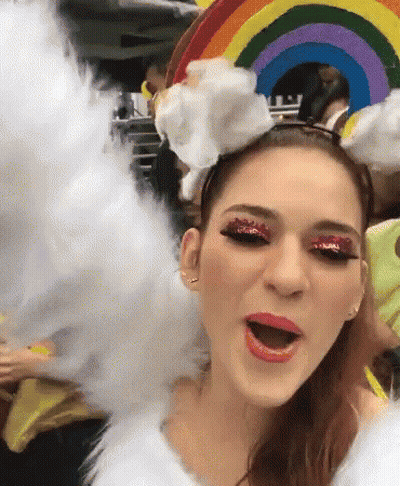 A Woman Is Wearing A Rainbow Headband And Cotton Candy GIF