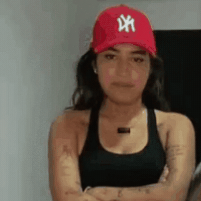 A Woman Is Wearing A Red Hat And A Black Tank Top . GIF