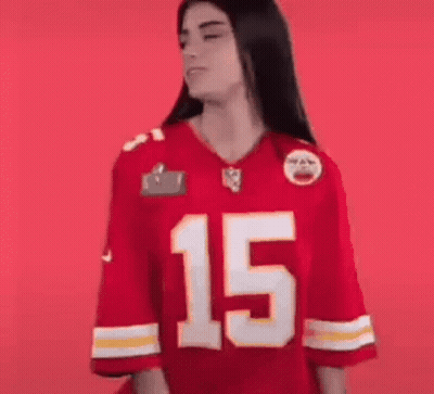 A Woman Is Wearing A Red Kansas City Chiefs Jersey And Smiling . GIF