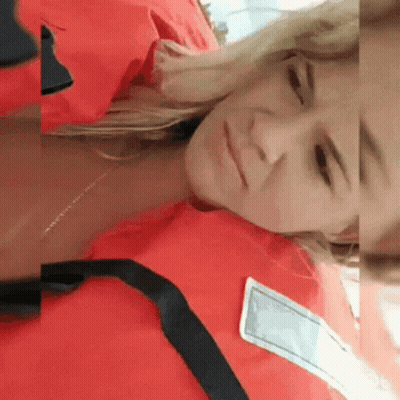 A Woman Is Wearing A Red Life Jacket And Laying Down GIF