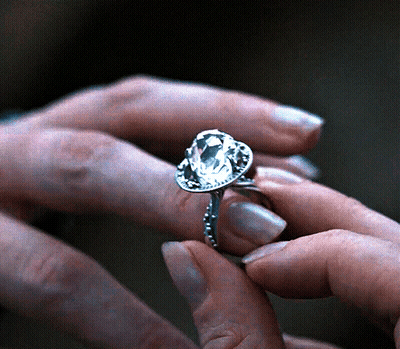 A Woman Is Wearing A Ring With A Large Diamond In It GIF