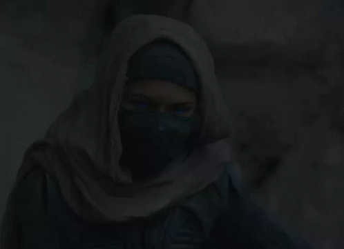 A Woman Is Wearing A Scarf Around Her Head In The Dark GIF