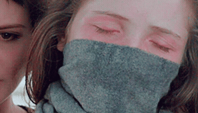 A Woman Is Wearing A Scarf Around Her Neck . GIF