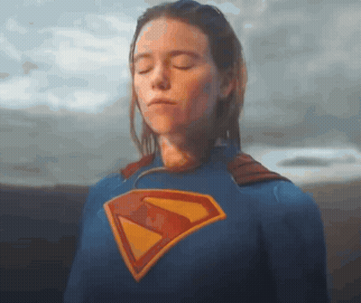 A Woman Is Wearing A Superman Costume With Her Eyes Closed . GIF