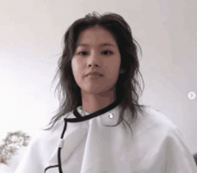 A Woman Is Wearing A White Cape Over Her Head And Looking At The Camera . GIF