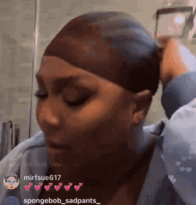 A Woman Is Wearing A Wig And Taking A Picture Of Herself In A Mirror . GIF
