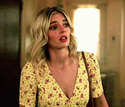 A Woman Is Wearing A Yellow Floral Top And A Brown Purse . GIF