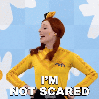 A Woman Is Wearing A Yellow Shirt That Says The Wiggles On It GIF