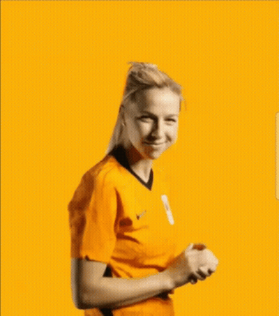 A Woman Is Wearing An Orange Shirt And Smiling Against A Blue Background . GIF