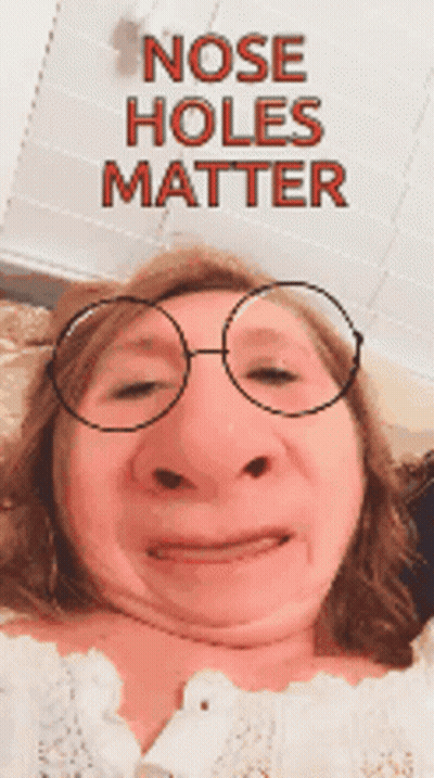A Woman Is Wearing Glasses And Making A Funny Face With The Words Nose Holes Matter Behind Her GIF