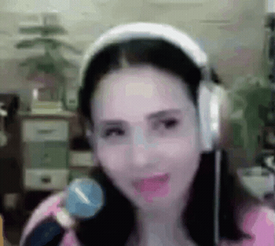 A Woman Is Wearing Headphones And Holding A Microphone In Her Hand . GIF