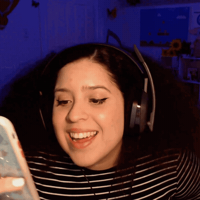 A Woman Is Wearing Headphones And Smiling While Looking At Her Phone GIF