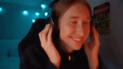 A Woman Is Wearing Headphones And Smiling While Sitting In Front Of A Computer Screen . GIF