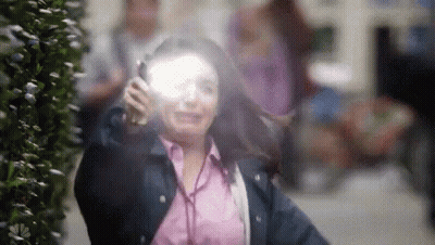 A Woman Is Wearing Headphones And Talking On A Cell Phone While Walking Down The Street . GIF