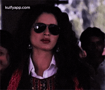 A Woman Is Wearing Sunglasses And A White Shirt . GIF