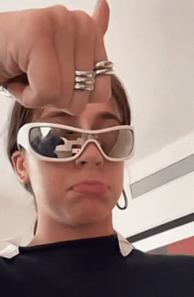 A Woman Is Wearing Sunglasses And Making A Funny Face . GIF