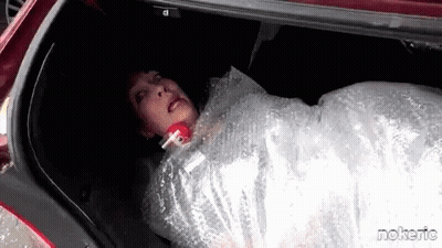 A Woman Is Wrapped In Bubble Wrap In The Back Of A Car . GIF