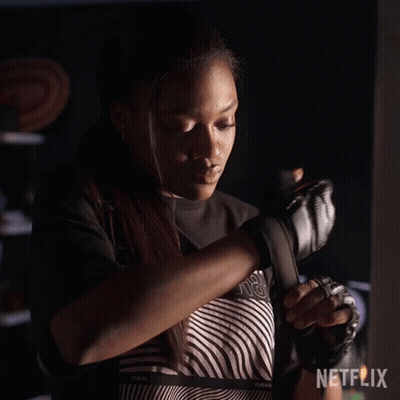 A Woman Is Wrapping Her Hands In Boxing Gloves . GIF