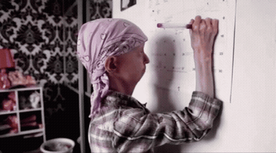 A Woman Is Writing On A Calendar With A Marker GIF