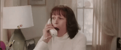 A Woman Is Yawning While Talking On A Phone In A Living Room . GIF