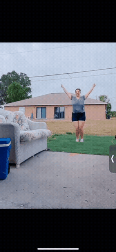 A Woman Jumping In The Air In Front Of A House GIF
