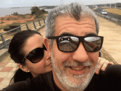 A Woman Kisses A Man 'S Cheek While Wearing Sunglasses GIF