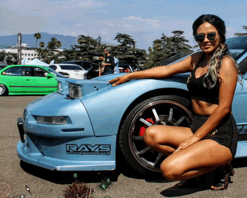 A Woman Kneeling In Front Of A Car With Rays Written On The Side GIF