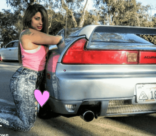 A Woman Kneeling In Front Of A Silver Acura GIF
