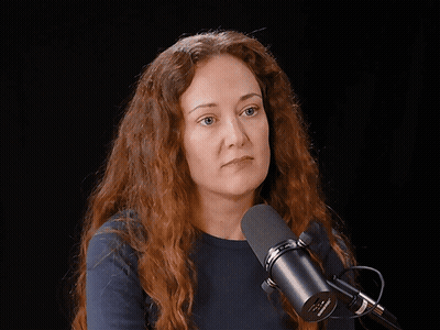 A Woman Laughs In Front Of A Microphone That Says Shure GIF