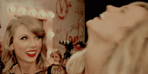 A Woman Laughs In Front Of A Mirror With The Word Love On The Wall GIF