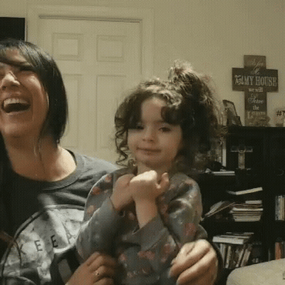A Woman Laughs While Holding A Little Girl In Front Of A Sign That Reads " My House " GIF