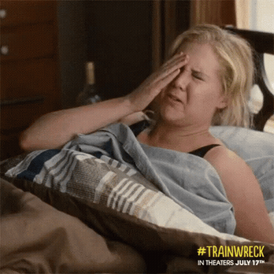 A Woman Laying In Bed With Her Hand On Her Forehead GIF