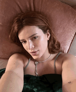 A Woman Laying On A Bed Wearing A Necklace And A Green Dress GIF