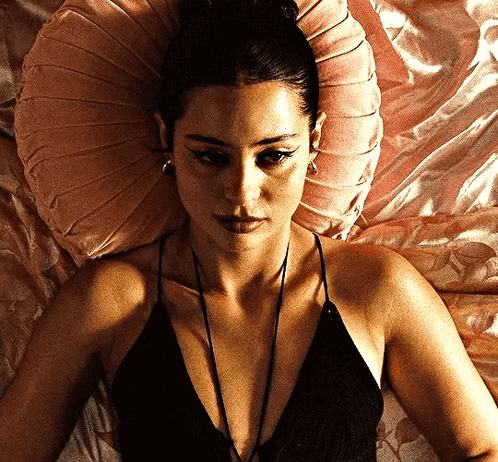 A Woman Laying On A Bed With A Pink Pillow GIF