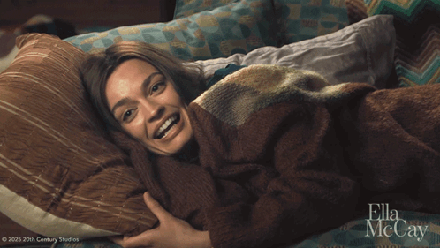 A Woman Laying On A Bed With Ella Mccay On The Bottom GIF
