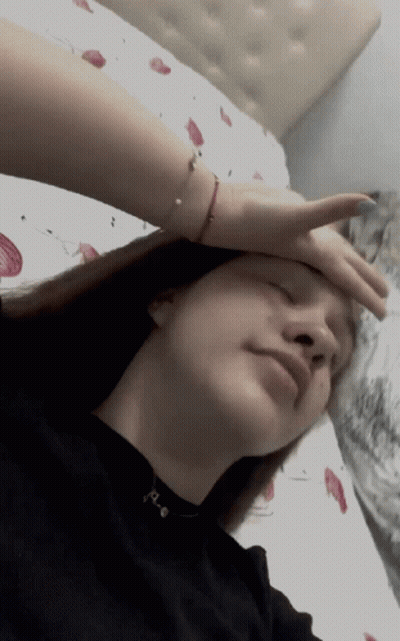 A Woman Laying On A Bed With Her Hand On Her Head GIF