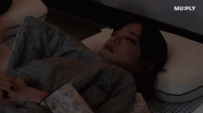A Woman Laying On A Bed With Muply Written On The Bottom Right GIF