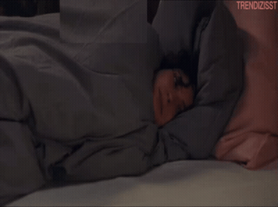 A Woman Laying On A Bed With The Words Trendizisst On The Bottom Right GIF