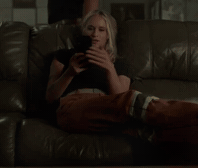 A Woman Laying On A Couch Looking At Her Phone GIF
