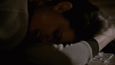 A Woman Laying On A Table With Her Head On Her Arm GIF